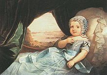 A painted portrait depicting an infant dressed in a blue cap, blue gown and propped up against a lace-trimmed pillow with a forested river scene visible through a curtained window in the background