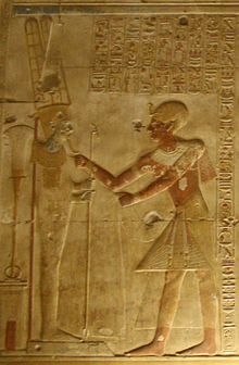 Relieve que demuestra un egipcio que alcanza a una figura masculina en un pedestal.