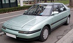 Un automóvil Mazda 323/protegé modelo 1994 en un aparcamiento público.